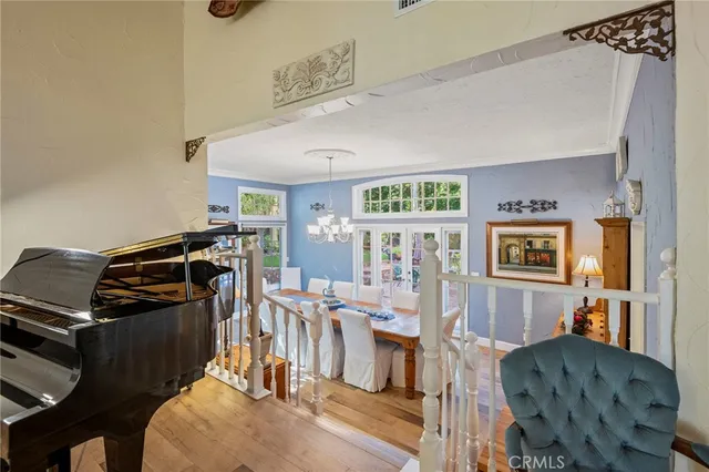 a dining room with wooden floor a chandelier a wooden table and chairs