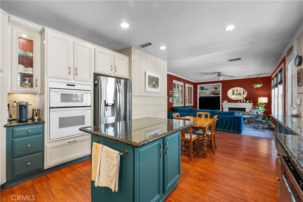 26214 Reade Place Stevenson Ranch, CA 91381 - Photo 19 of 58 a kitchen with stainless steel appliances granite countertop a refrigerator a stove top oven a dining table and chairs with wooden floor