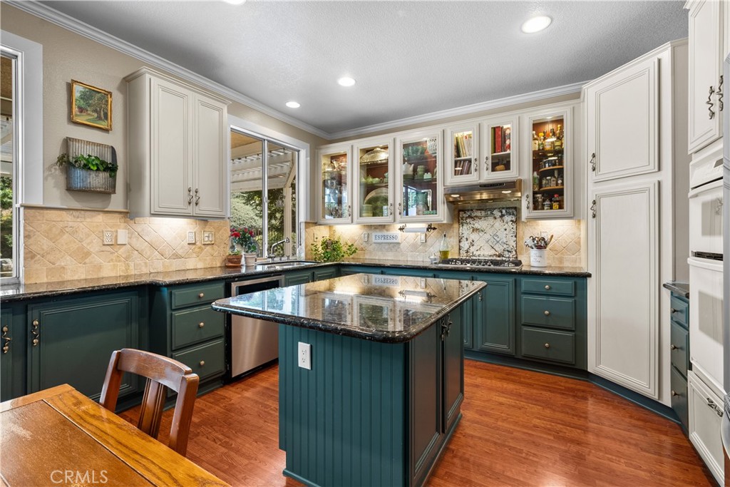 26214 Reade Place Stevenson Ranch, CA 91381 - Photo 20 of 58 a kitchen with kitchen island granite countertop a sink cabinets and wooden floor
