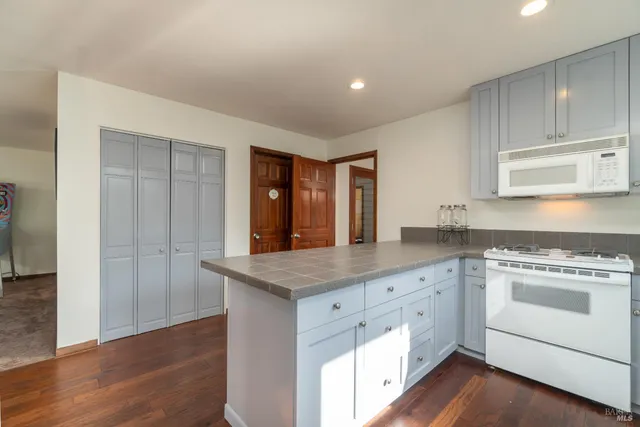 a kitchen with granite countertop white cabinets and a wooden floor