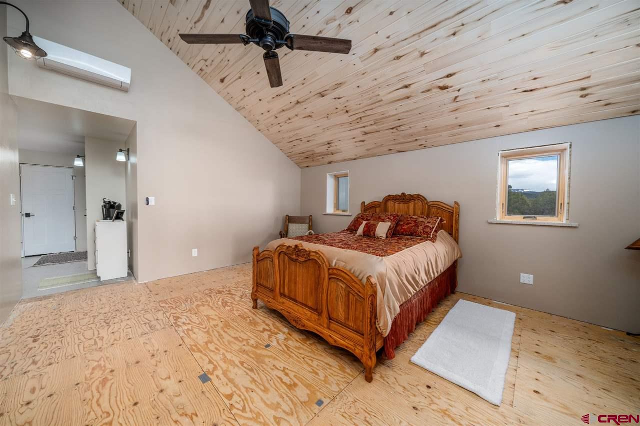 20885 Mesawood Road Cedaredge, CO 81413 - Photo 25 of 35 a bedroom with a bed and wooden floor