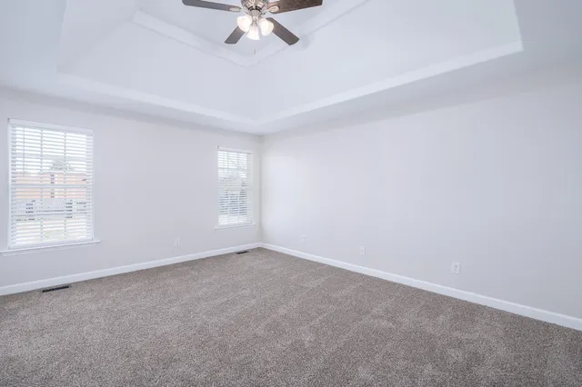 an empty room with a chandelier fan and windows