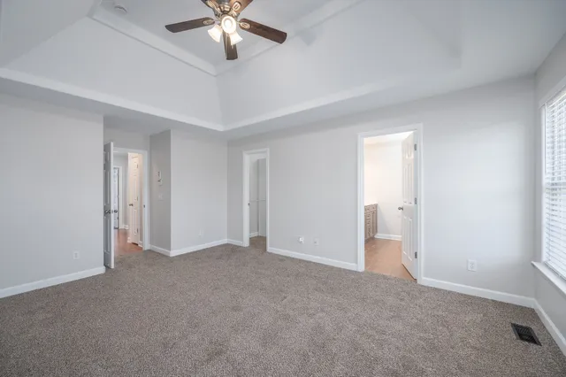 a view of an empty room and chandelier fan