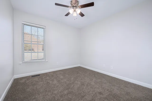 an empty room with a window and a fan