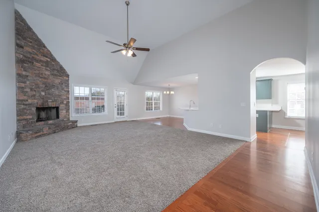 a view of a livingroom with a fireplace a ceiling fan and wooden floor