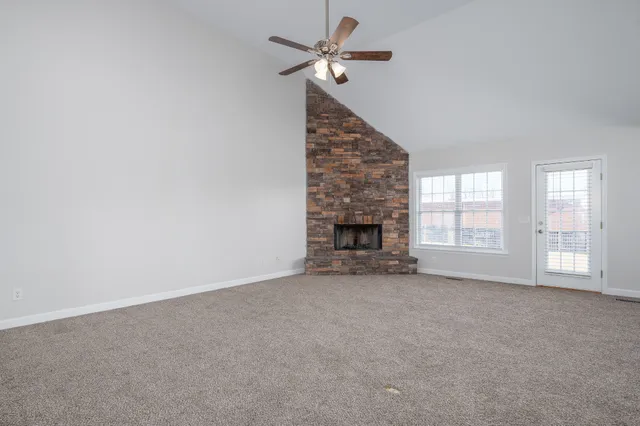 an empty room with windows and fireplace