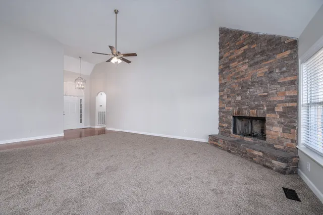 an empty room with a fireplace and a ceiling fan