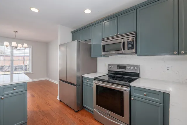 a kitchen with cabinets stainless steel appliances and wooden floor