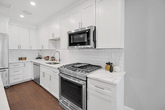 a kitchen with cabinets stainless steel appliances and sink