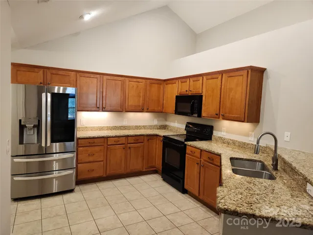 a kitchen with granite countertop a refrigerator and a stove top oven