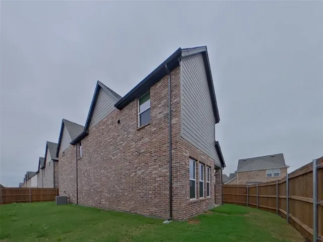 a view of a house with brick walls and a yard