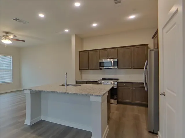 a kitchen with stainless steel appliances granite countertop a stove a sink and a refrigerator