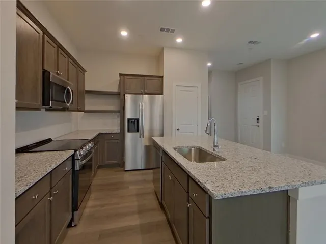 a kitchen with granite countertop kitchen island stainless steel appliances a sink stove and refrigerator