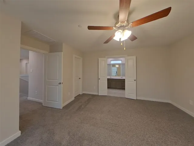 an empty room with chandelier fan and windows