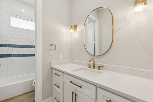 a bathroom with a sink a mirror a vanity and a bathtub
