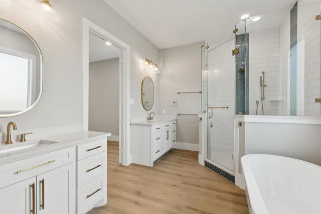 a spacious bathroom with a double vanity sink a mirror a toilet and a shower