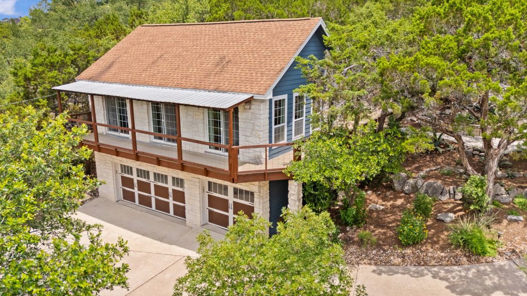 10800 Beach Road Leander, TX 78641 - Photo 24 of 39 Perched amidst lush trees, this property showcases a dual-material facade with a generous second-story deck.