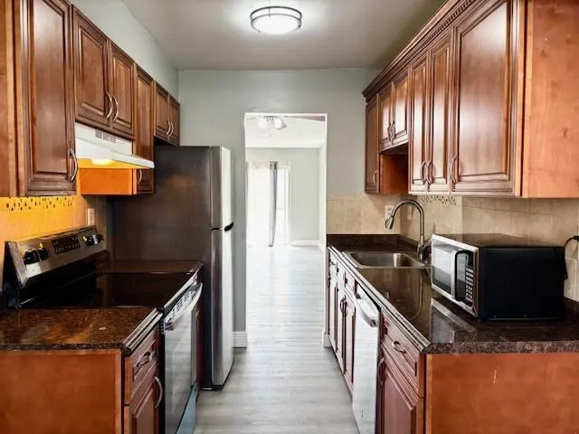 a kitchen with stainless steel appliances granite countertop a stove a sink and a microwave