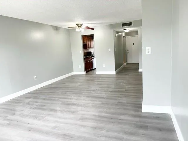 a view of a hallway with wooden floor and a large mirror