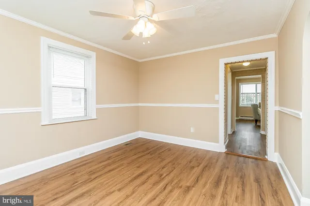 an empty room with wooden floor closet and windows