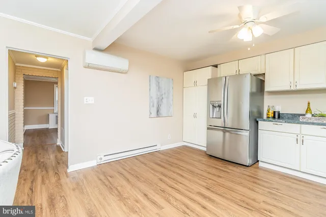 a large white kitchen with granite countertop a lot of counter space and wooden floor