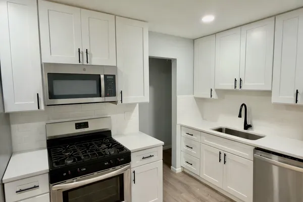 a kitchen with white cabinets and appliances