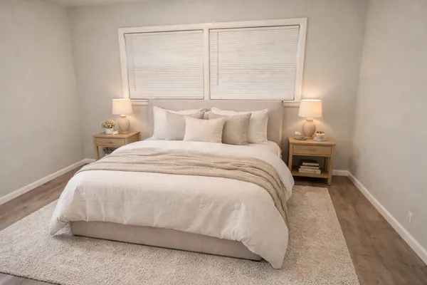 a large white bed in a bedroom next to a window