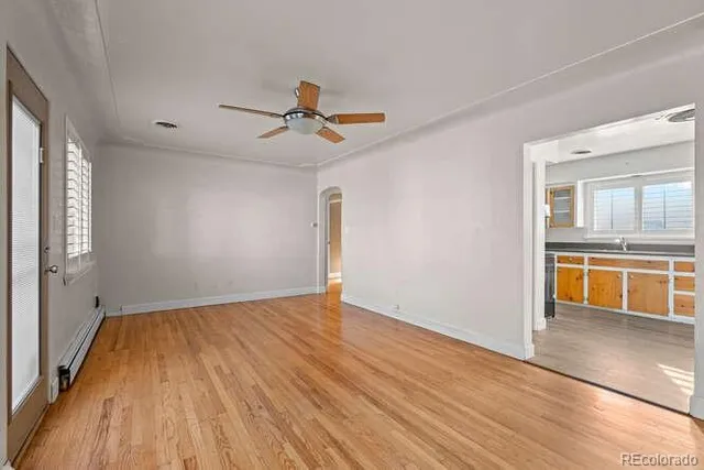 a view of empty room with wooden floor and fan