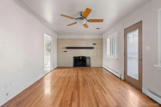 a view of a livingroom with a fireplace a ceiling fan and windows
