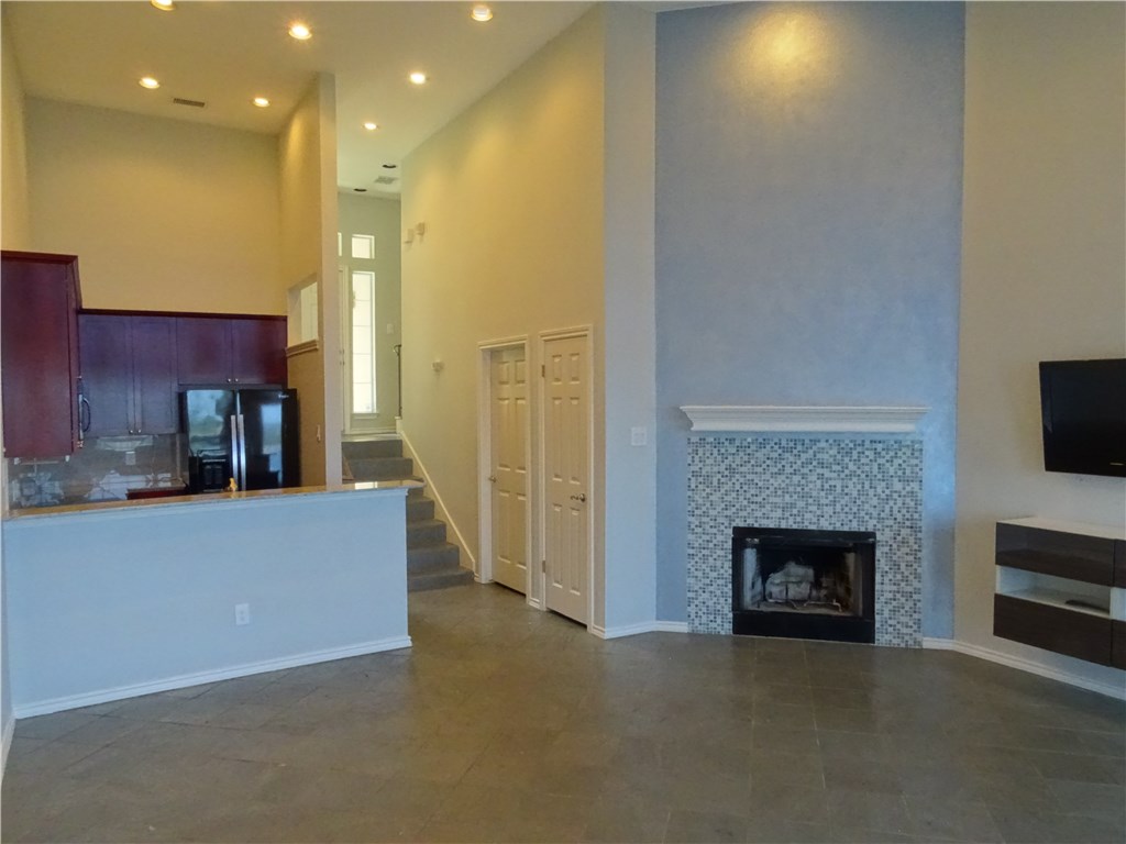 2918 Ranch Road 620, Unit K170 Austin, TX 78734 - Photo 7 of 22 Vast living area featuring high ceilings, a mosaic-tiled fireplace, and a sleek kitchen with rich cabinetry.