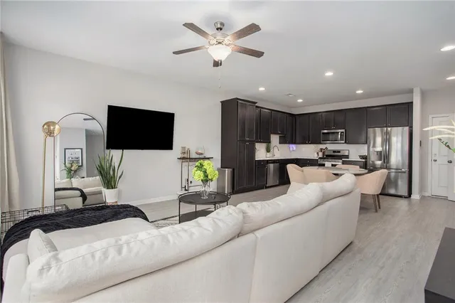a living room with furniture kitchen view and a flat screen tv