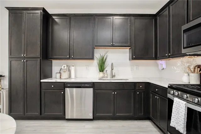 a kitchen with stainless steel appliances granite countertop a stove a sink and a microwave