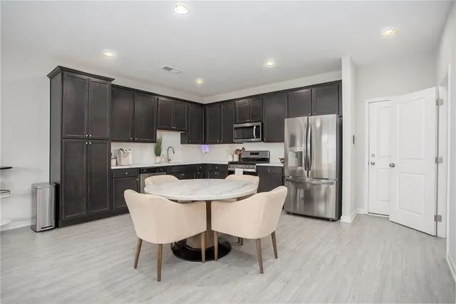 a kitchen with kitchen island a refrigerator a stove a microwave oven a sink and chairs