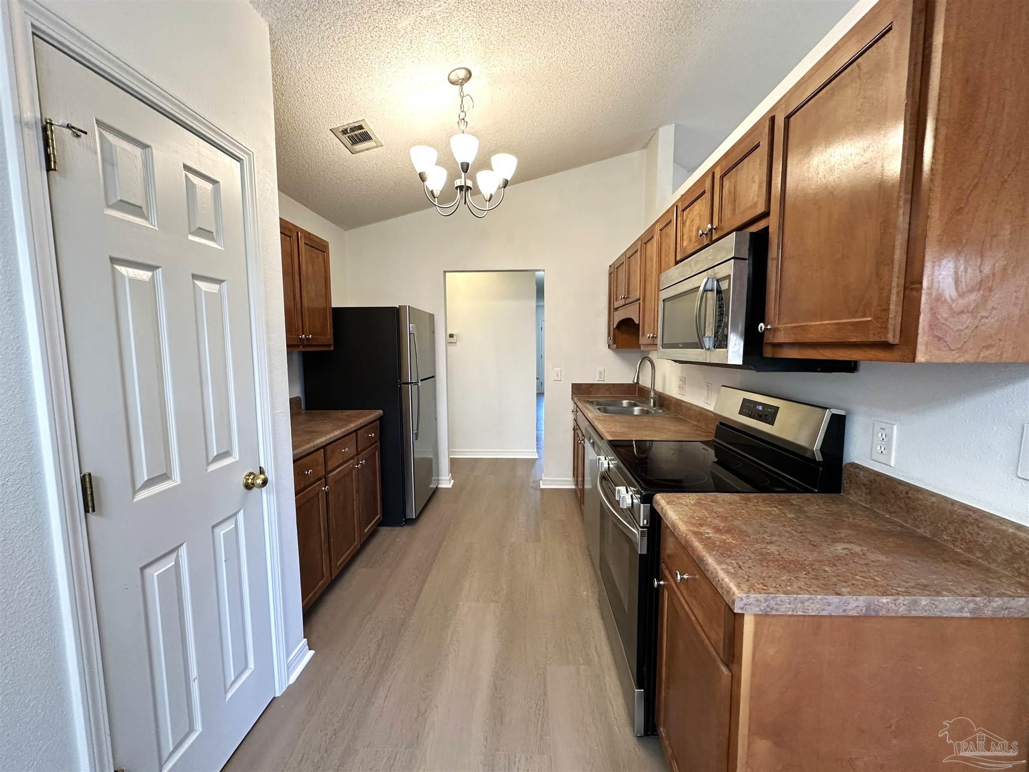 7959 Cayenne Way Pensacola, FL 32526 - Photo 4 of 19 a kitchen with stainless steel appliances granite countertop a refrigerator a stove top oven a sink dishwasher and wooden cabinets