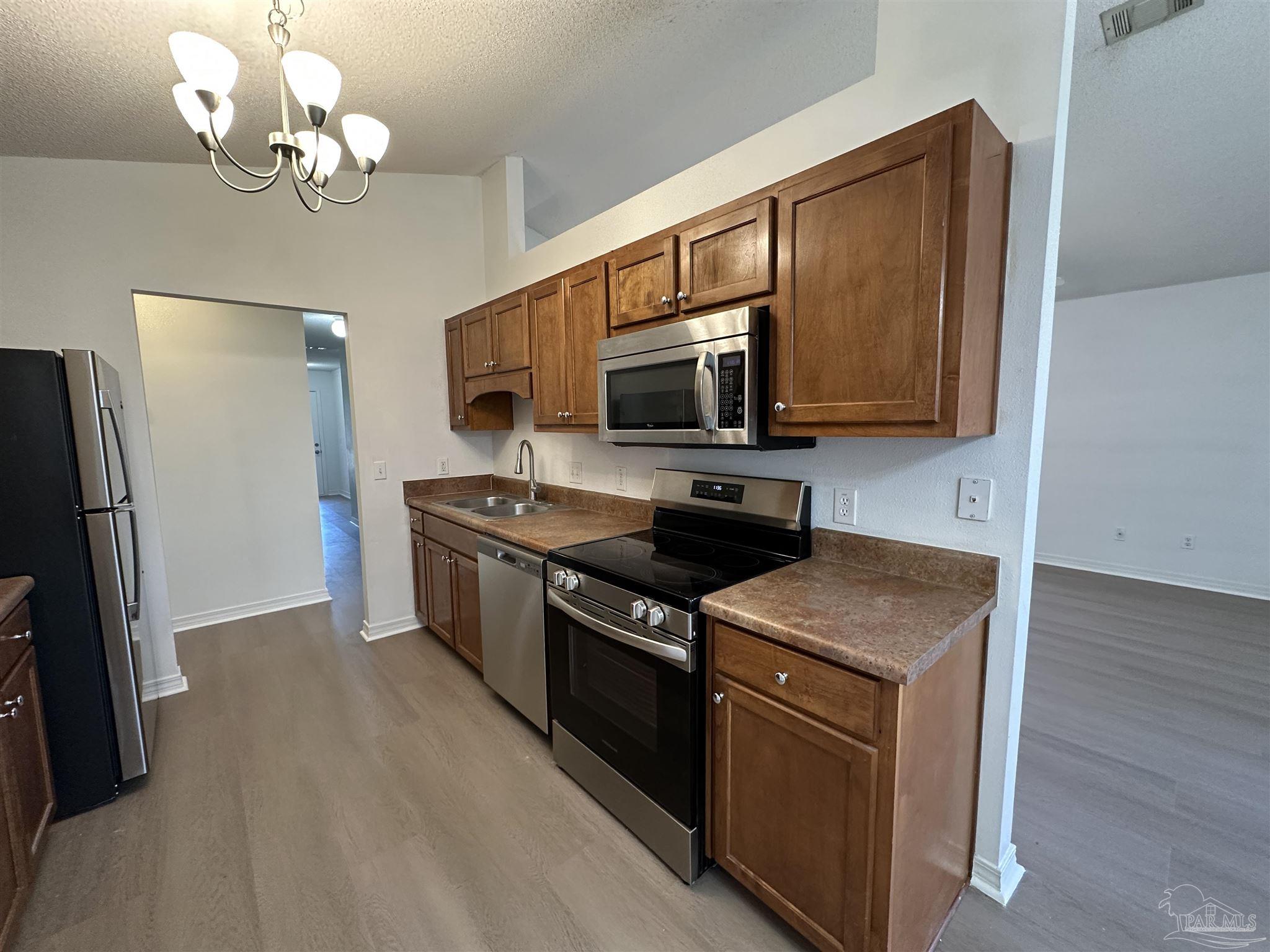 7959 Cayenne Way Pensacola, FL 32526 - Photo 5 of 19 a kitchen with stainless steel appliances granite countertop a stove a sink dishwasher a refrigerator and a microwave oven with wooden floor