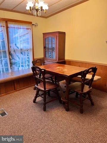 a view of a dining room with furniture a chandelier and a window