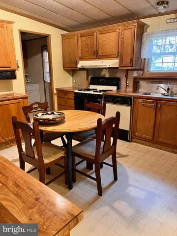 a kitchen with stainless steel appliances kitchen island granite countertop a table chairs and a refrigerator