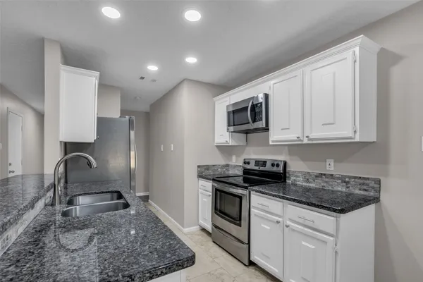 a kitchen with granite countertop a sink a stove and cabinets
