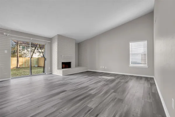 an empty room with wooden floor and a fireplace