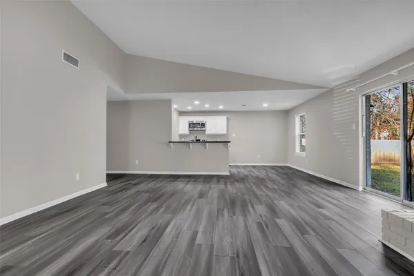 a view of empty room with wooden floor and windows