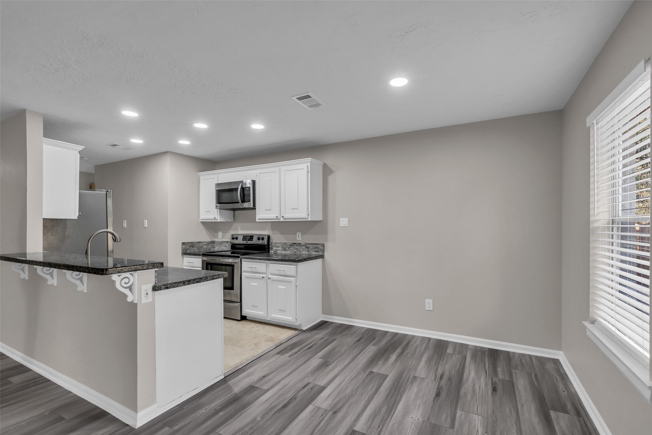 8 Still Glen Court Spring, TX 77381 - Photo 8 of 23 a kitchen with stainless steel appliances granite countertop a stove top oven a sink dishwasher a refrigerator and white cabinets with wooden floor