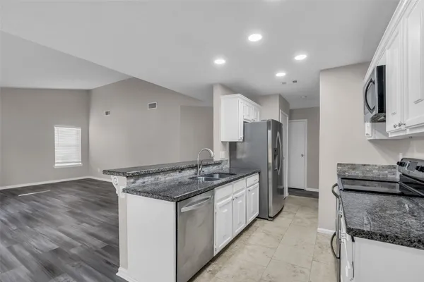 a kitchen that has a lot of cabinets in it and stainless steel appliances