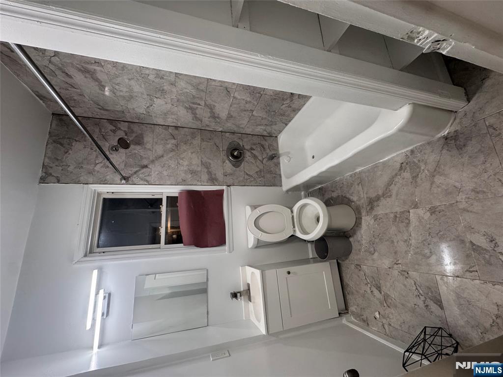 121-123 Butler Street, Unit 121 Paterson, NJ 07524 - Photo 6 of 6 a bathroom with a sink a toilet a mirror a bathtub and shower