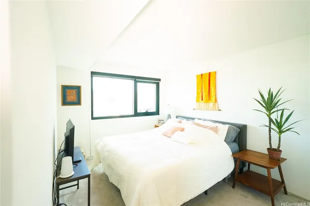 a bedroom with a bed and a potted plant