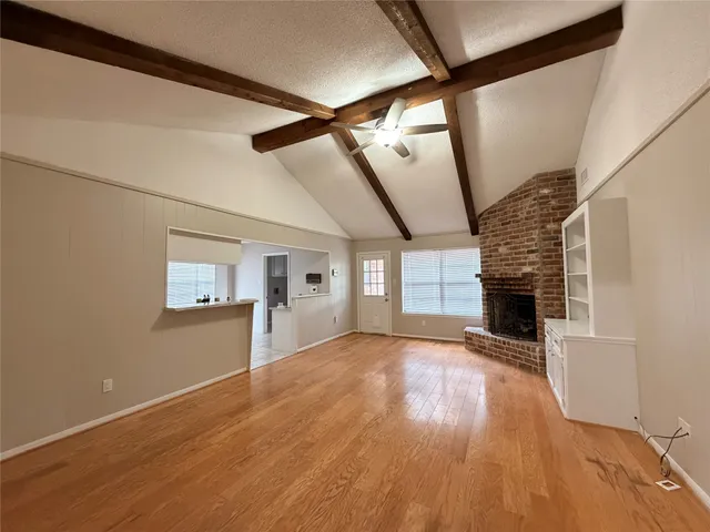 a view of empty room with wooden floor and fireplace