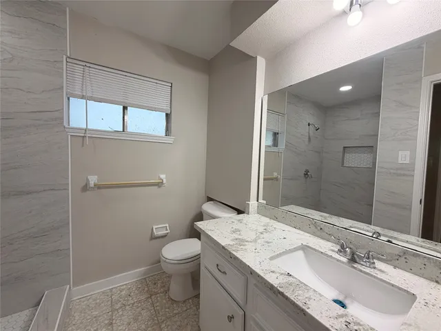 a bathroom with a granite countertop sink a toilet and shower