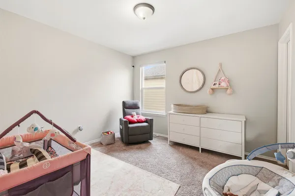 a room with a baby bed baby crib and dresser