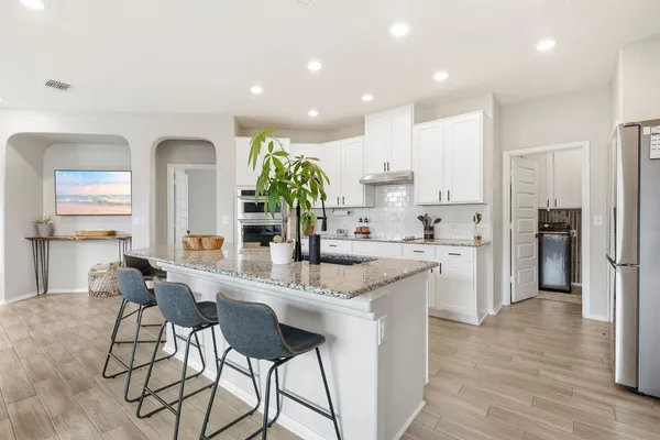 a kitchen with stainless steel appliances kitchen island granite countertop a refrigerator and a sink