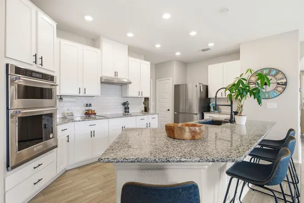 a kitchen with granite countertop kitchen island stainless steel appliances a stove a sink a microwave a refrigerator and cabinets