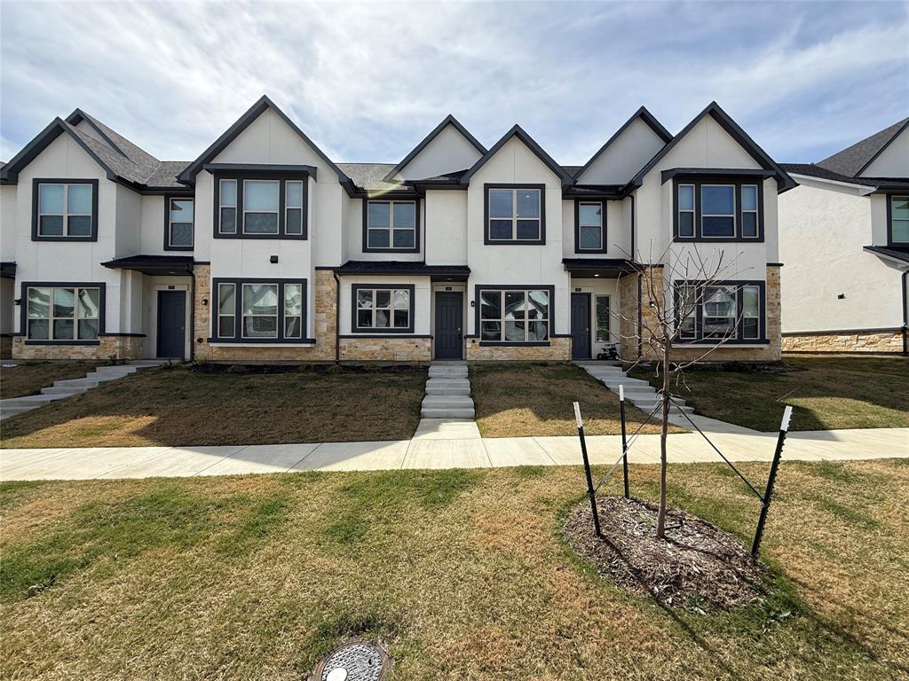 View of front of house with stone siding, stucco siding, and a front yard